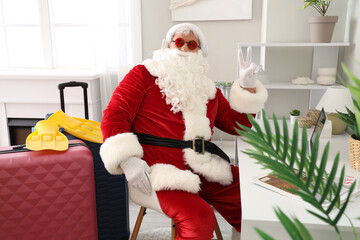 Santa Claus with headphones showing victory gesture at home. Christmas in July