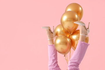 Legs of young woman with air balloons on pink background