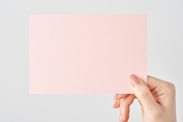 ピンク色の紙を持つ女性の手元