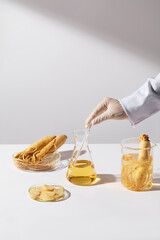 An erlenmeyer flask with yellow liquid being stirred by a scientist hand, placed in center of white...