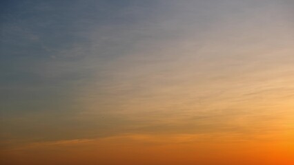 Fototapeta premium A soft gradient from orange at the horizon to a muted blue at the top, with delicate, wispy clouds enhancing the serene and tranquil atmosphere of the sunset. Cloud background. 