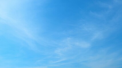 A serene blue sky with light, wispy clouds scattered across. The sky's bright and even blue tone...