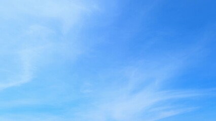 A clear blue sky with a few light, wispy clouds spread across. The sky's bright blue hue conveys a...