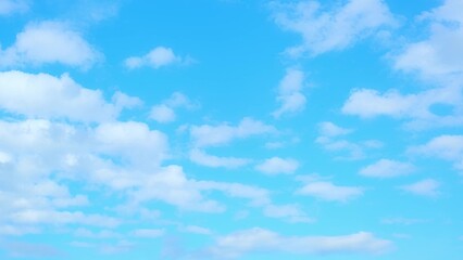 A bright blue sky with numerous small, fluffy white clouds scattered across it. The clouds are evenly dispersed, creating a peaceful and serene scene, perfect for a sunny day. Horizon background.
