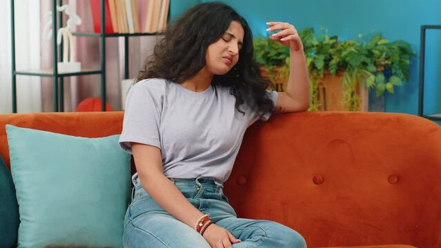Portrait of sad Indian woman girl sitting at home looks pensive thinks over life concerns or unrequited love, suffers from unfair situation. Problem, break up, depressed feeling bad annoyed, burnout