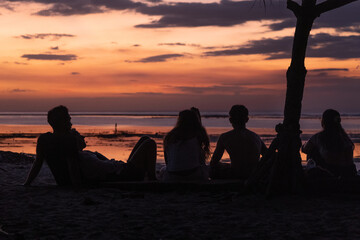 Group of friends, male and female, watching  the sunset at Scar Reef, West Sumbawa.