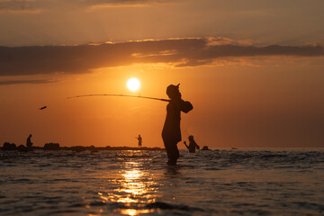 Young local fisherman with hat fishing at sunset. 