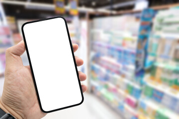Hand holding blank screen smartphone for copy space on blurred Miscellaneous Product shelf. e-commerce app shopping mockup. social media, payment and shopping online concept.