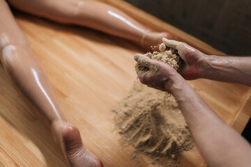 High-angle view of unrecognizable Ayurvedic massage practitioner male mixing heated sand on massage...
