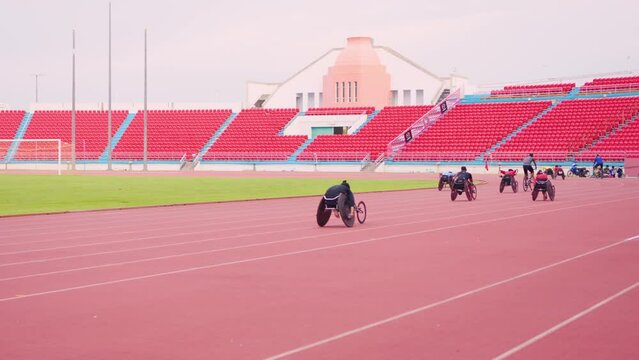Professional man para-athletes disabled practice handcycling in stadium.