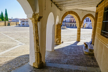 Stone arches with whitewashed walls in the main square of the Cáceres town of Garrovillas de...