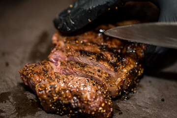 Top view of ultra-thin slices of rare, large roast beef on an Australian tomahawk steak. Revealing pink flesh Beautiful golden brown shell Served on a black butcher knife on the table, yes.