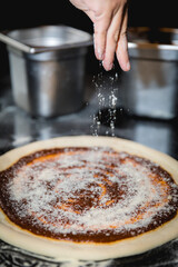 A chef preparing a cheese and basil pizza