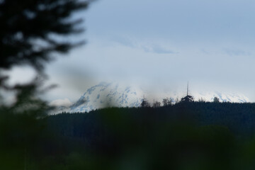 Mount Rainier hidden behind a layer of clouds as seen from a river in Washington State.