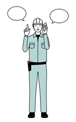 Man in helmet and workwear pointing while on the phone.