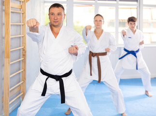Group of athletic people in kimonos try new fighting techniques at karate lessons © JackF