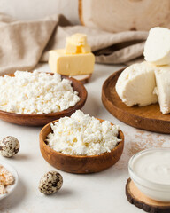 Assorted dairy products including cottage cheese, sour cream, and butter on a rustic wooden setup