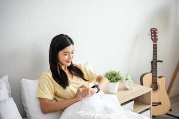 Asian young beautiful woman looking on smartwatch checking sleep rate. 