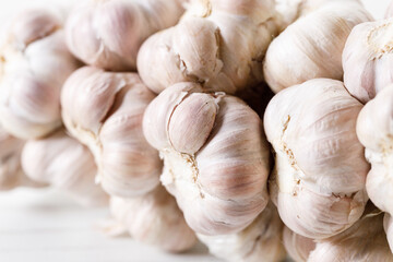 Ripe organic garlic clove and bulb on white wooden background.  Close-up. Selective focus.