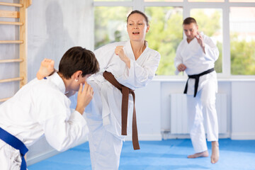 Guy and girl training wrestling fighting. Athletes repeat and practice basic techniques of kicks and punches. Coach prepares martial arts athletes for competitive program