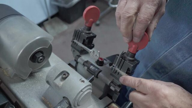 Latin man working on key duplication with special machinery. Concept of focus and concentration. Close-up of hands.
