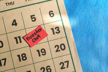 Booster dose vaccine shot schedule concept. Written reminder note on calendar.