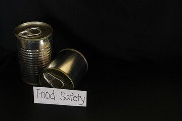Food safety concept. Labeled canned food in dark black background.