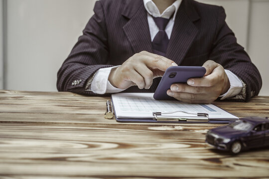 A businessman in a formal suit signs a contract, hands close up, highlighting financial terms like amortization, APR, and asset management, documents symbolizing various loan and insurance concepts.