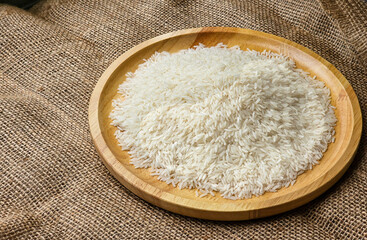 Side view, rice grains on a wooden plate. sackcloth background