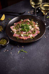 tuna carpaccio - slices of fresh raw tuna fillet on black ceramic plate