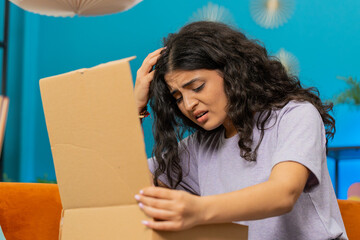 Angry dissatisfied shopper Indian woman unpacking parcel feeling upset and confused with wrong...
