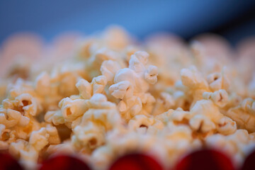 Macro close up Photo of popcorn in a red box against a blue bokeh background, creating a delicious and cinematic scene.