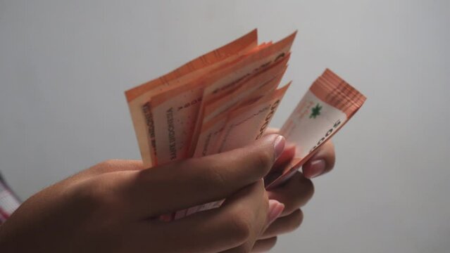 person counting money Indonesian rupiah on white background