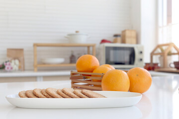 Freshly baked homemade cookies in plate on counter at home kitchen, sweet cookie with blurred background of orange fruit and kitchen.