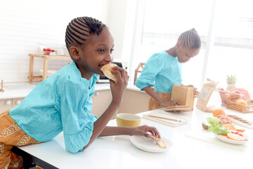 Twin sister girl with curly hair braid African hairstyle have meal together in kitchen Happy kid...