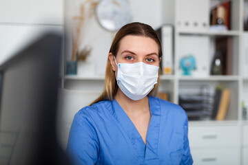 Medical female worker enters patient data into laptop