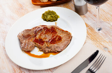 Medium rare beef steak with piquant pesto served on white plate..