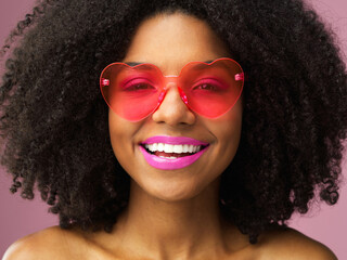 Woman, portrait and smile, curly hair and heart sunglasses for makeup or comic person isolated in...