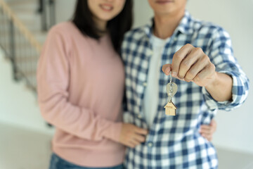 Moving house, relocation. Husband hold key house keychain in new apartment. move in new home. Buy...