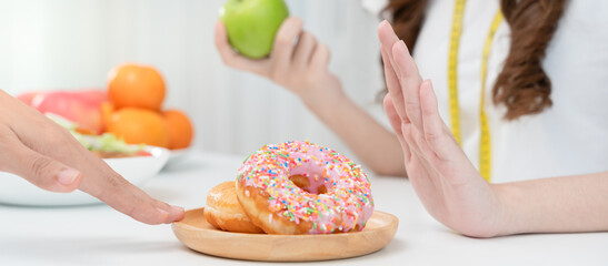 Diet and dieting. Beauty slim female body confuse donut. Woman in exercise clothes achieves weight loss goal for healthy life, crazy about thinness, thin waist, nutritionist.
