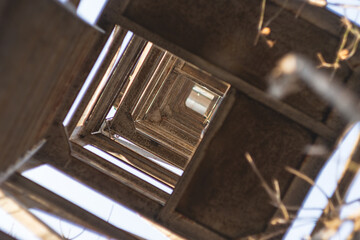 Bottom-up perspective of the rusty metal lattice structure that forms part of the tower. The structure forms an intricate pattern of squares and rectangles that extend into the blue sky.