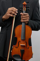 Closeup of a man in a suit with a violin and a bow in hands, ready to play music in a dramatic...