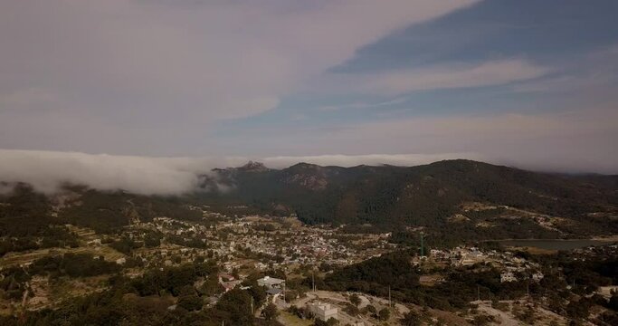 Aerial drone shot of mountain range of pachuca mexico with green and yellow fields, bank of clouds 200% speed
