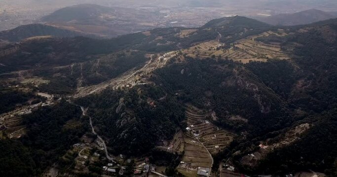 Aerial drone shot of mountain range of pachuca mexico with green and yellow fields