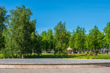 Open stone stage in the park on the background of summer  public park as pedestal for your creativity.
