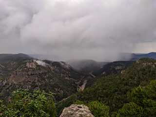 Green mountain landscape, with storm clouds, rainy day in a ravine with the river in the background