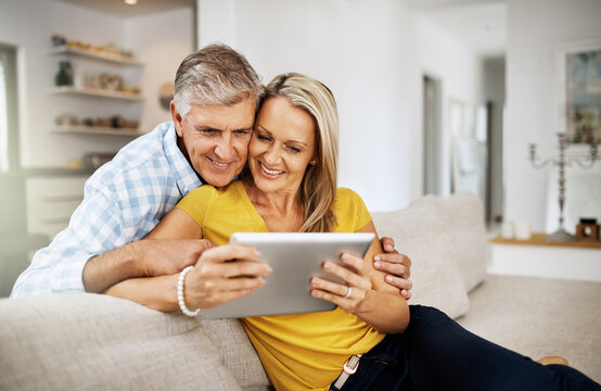 Couple, hug and tablet on sofa for social media, news and online on couch in living room. Technology, internet or app on digital website in home, man or woman mature people in lounge with touchscreen