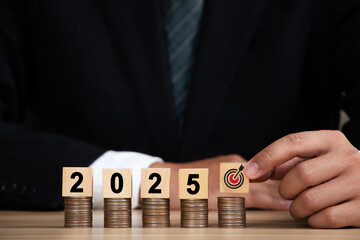  2025 new year budget planning concept. Businessman hand is holding a wooden block with a target...