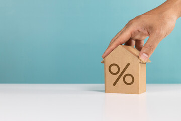 Interest percent, money saving, investing for home lone and property profit. Hand hold miniature house with interest percent symbol icon for real estate investment