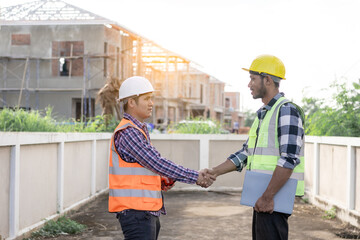 Smiling engineers holding hands at construction site and happy architects holding hands. African construction manager business teamwork. Cooperation. Successful collaboration concept.